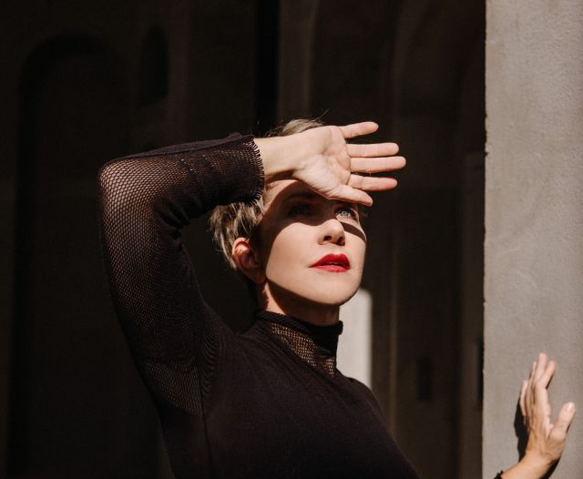 Foto von Joyce DiDonato – Die Mezzosopranistin in dramatischer Pose, mit der Hand vor der Sonne, in einem schwarzen Outfit.