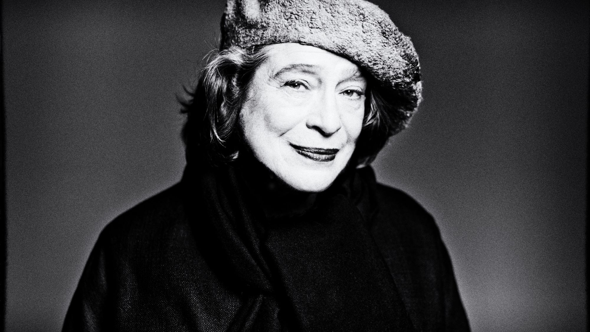 Foto von Elisabeth Leonskaja – Schwarzweissbild der Pianistin, die vor einem  Grauen Hintergrund steht und zur Seite blickt, man sieht beinahe nur ihre Silhouette