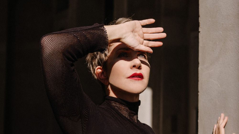 Foto von Joyce DiDonato – Die Mezzosopranistin in dramatischer Pose, mit der Hand vor der Sonne, in einem schwarzen Outfit.