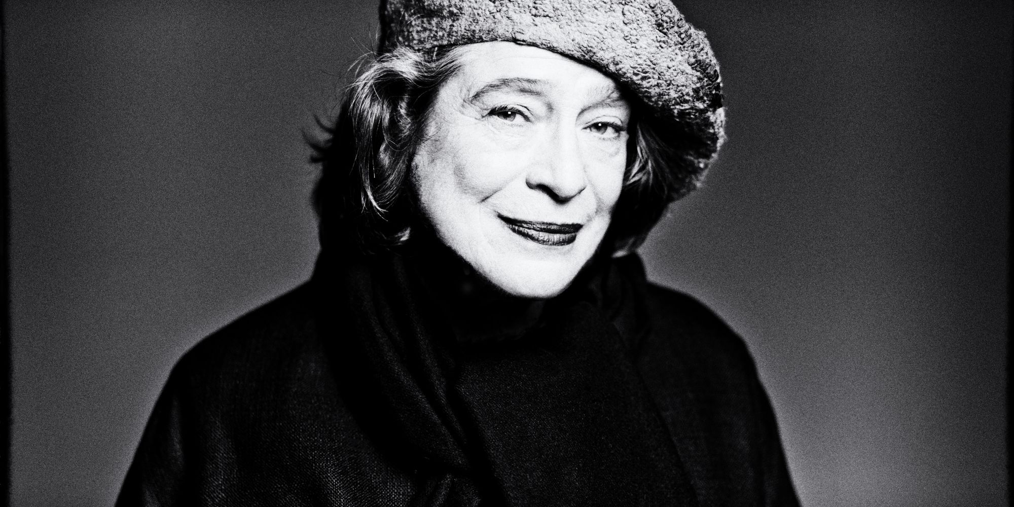 Foto von Elisabeth Leonskaja – Schwarzweissbild der Pianistin, die vor einem  Grauen Hintergrund steht und zur Seite blickt, man sieht beinahe nur ihre Silhouette