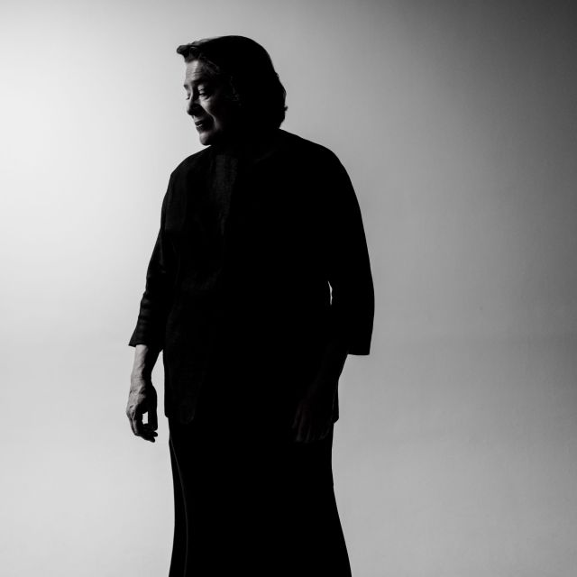 Foto von Elisabeth Leonskaja – Schwarzweissbild der Pianistin, die vor einem  Grauen Hintergrund steht und zur Seite blickt, man sieht beinahe nur ihre Silhouette