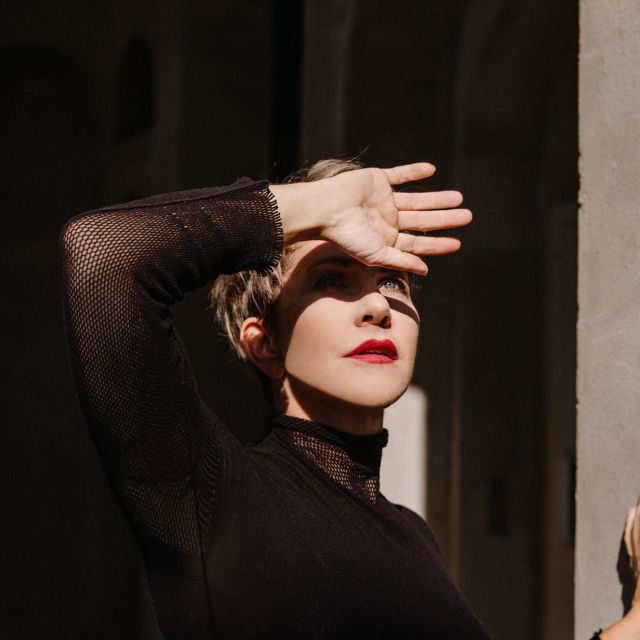 Foto von Joyce DiDonato – Die Mezzosopranistin in dramatischer Pose, mit der Hand vor der Sonne, in einem schwarzen Outfit.