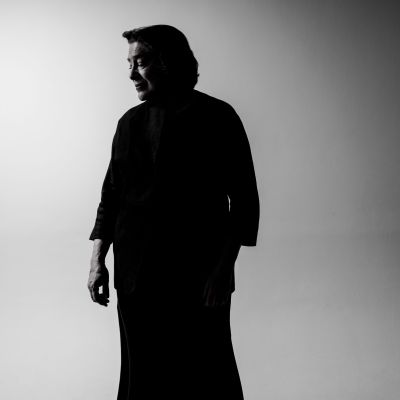 Foto von Elisabeth Leonskaja – Schwarzweissbild der Pianistin, die vor einem  Grauen Hintergrund steht und zur Seite blickt, man sieht beinahe nur ihre Silhouette