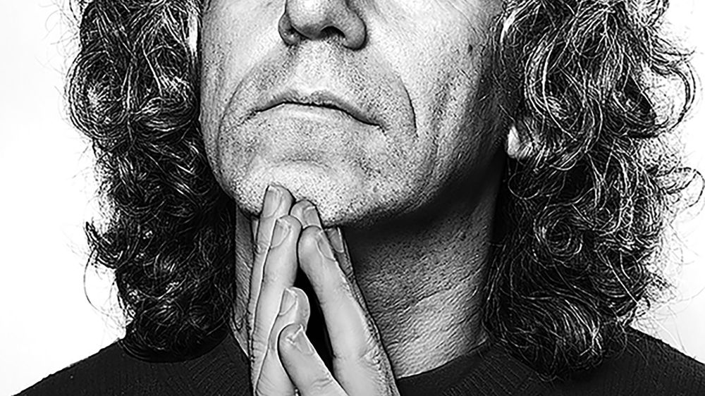 Foto von Steven Isserlis – schwarz-weiss-Porträt des Cellisten mit markanten Locken, nachdenklich mit gefalteten Händen in die Kamera blickend.
